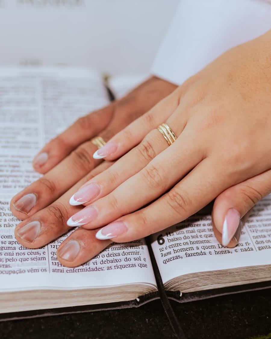 Mãos de um casal com alianças Dízer, sobre a Bíblia